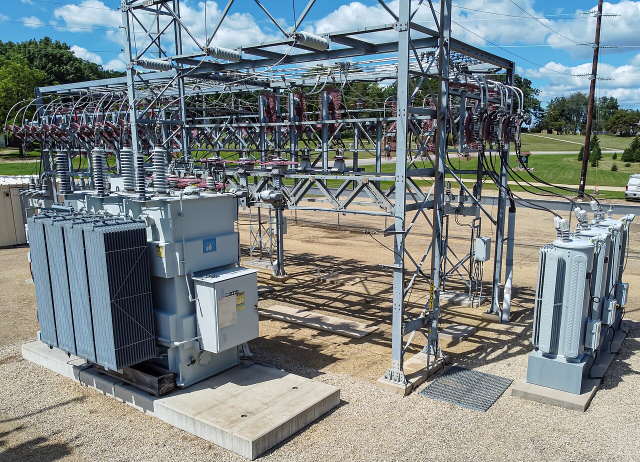 Outdoor electrical transformers and switchgear at a substation under a blue sky