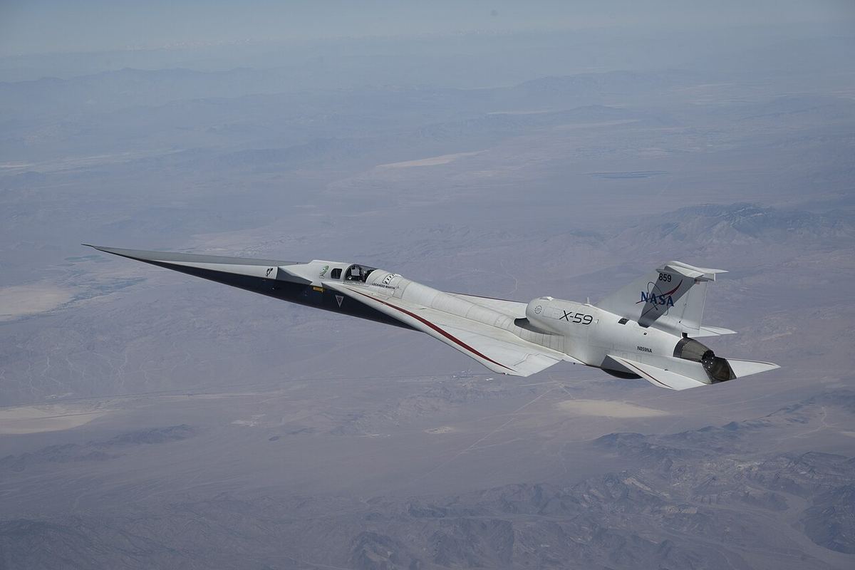 NASA's long, needle-nosed X-59 research jet flies high above the brown Mojave Desert