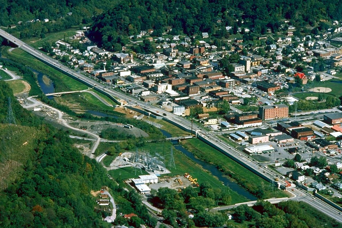 An aerial view of the small mountain town of Harlan, Ky., with a river, floodwall and highway running through green hills
