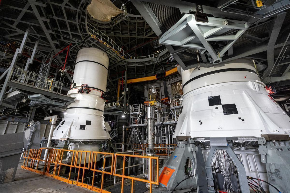 The white aft segments of two giant rocket boosters stand on a launch platform inside NASA's Vehicle Assembly Building