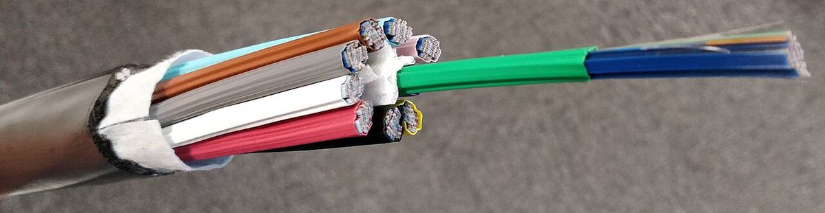 A cut-open fiber optic ribbon cable showing colored bundles of thin glass fibers