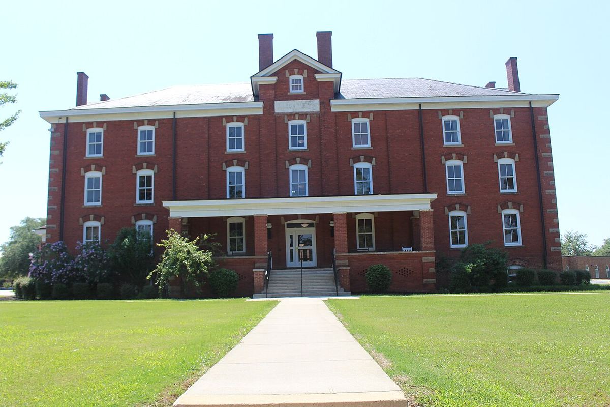 Red-brick Huntington Hall at Fort Valley State University with a white porch, green lawn and blue sky